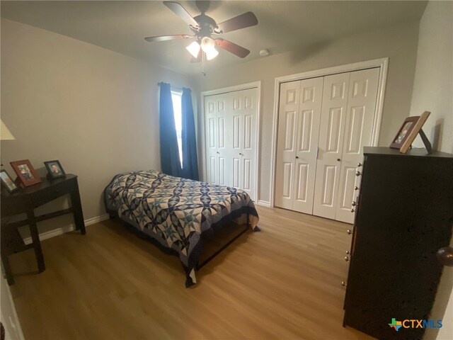 bedroom featuring baseboards, multiple closets, light wood finished floors, and ceiling fan
