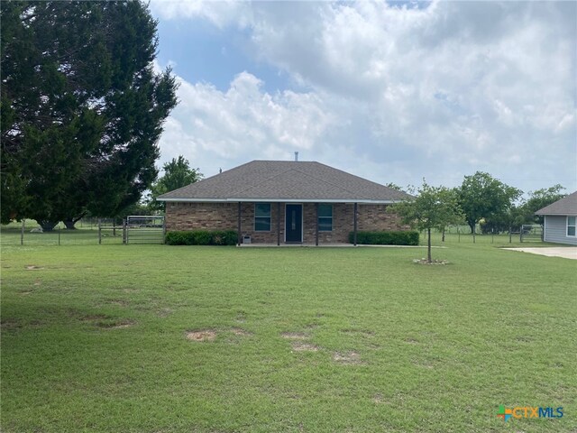 view of front of property with brick siding, fence, a front yard, and roof with shingles