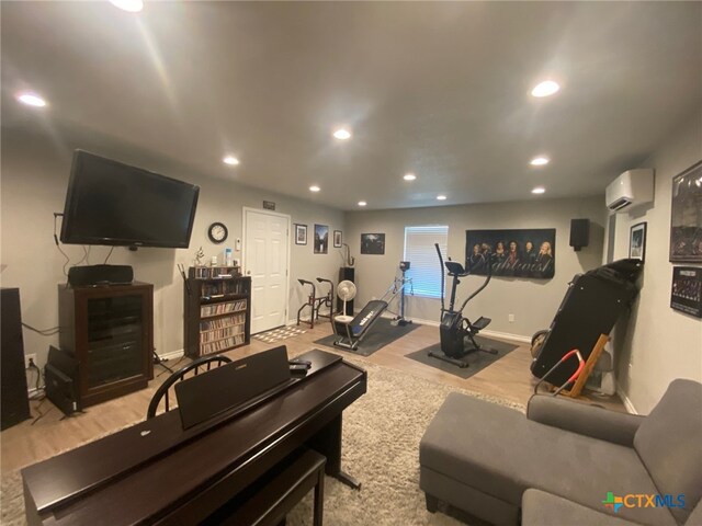 workout area featuring baseboards, a wall mounted AC, and wood finished floors