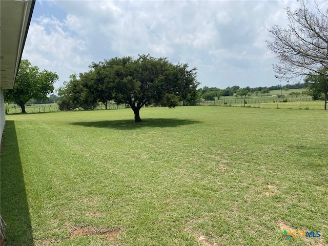 view of yard with fence and a rural view