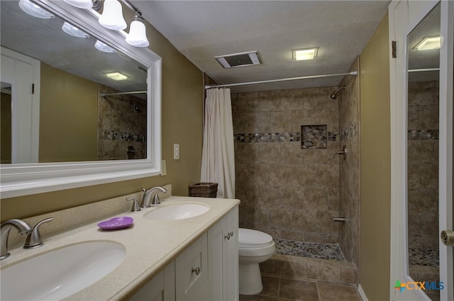 bathroom featuring a textured ceiling, toilet, walk in shower, and vanity