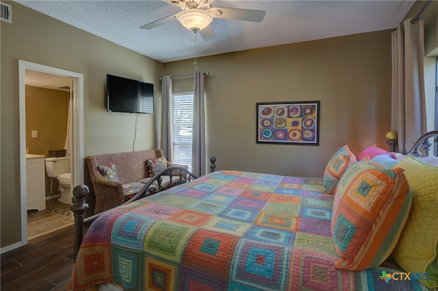 bedroom with a textured ceiling, ensuite bathroom, dark hardwood / wood-style floors, and ceiling fan