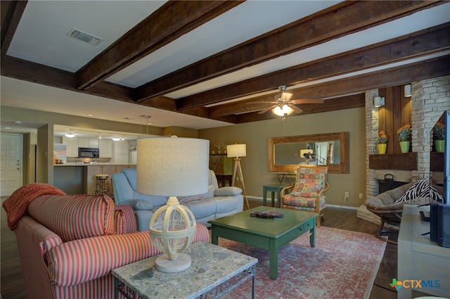 living room with ceiling fan, beamed ceiling, dark hardwood / wood-style floors, and a fireplace