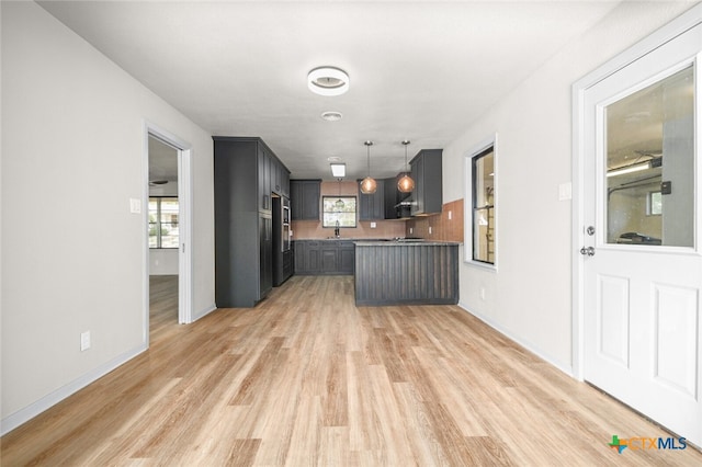 kitchen with tasteful backsplash, decorative light fixtures, plenty of natural light, and light wood-type flooring