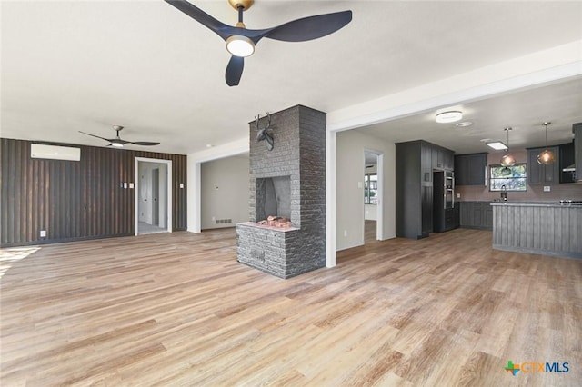 unfurnished living room with ceiling fan, light hardwood / wood-style floors, and a brick fireplace