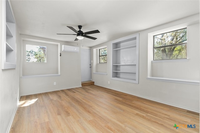 spare room with ceiling fan, a wall mounted AC, built in features, and a wealth of natural light