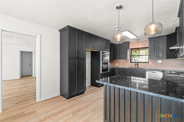 kitchen with appliances with stainless steel finishes, tasteful backsplash, dark stone countertops, pendant lighting, and sink