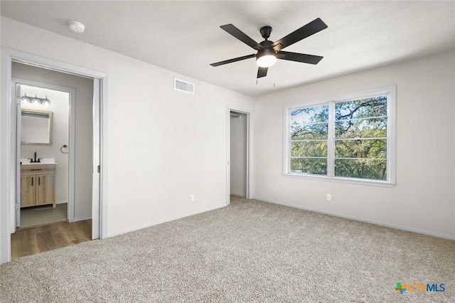 unfurnished bedroom with ceiling fan, connected bathroom, and carpet