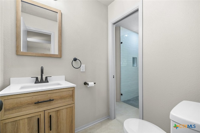 bathroom with toilet, vanity, and tiled shower