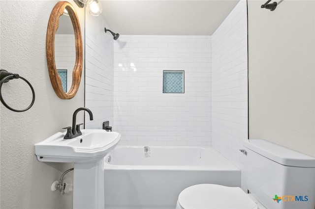 bathroom with toilet and tiled shower / bath