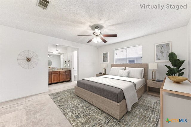 12219 Mosley Ln, Austin, TX 78727 - bedroom with light colored carpet, ensuite bathroom, ceiling fan, and a textured ceiling