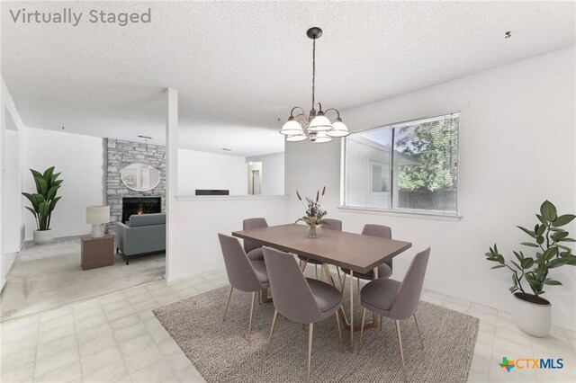12219 Mosley Ln, Austin, TX 78727 - dining space featuring light floors, a chandelier, a stone fireplace, and a textured ceiling