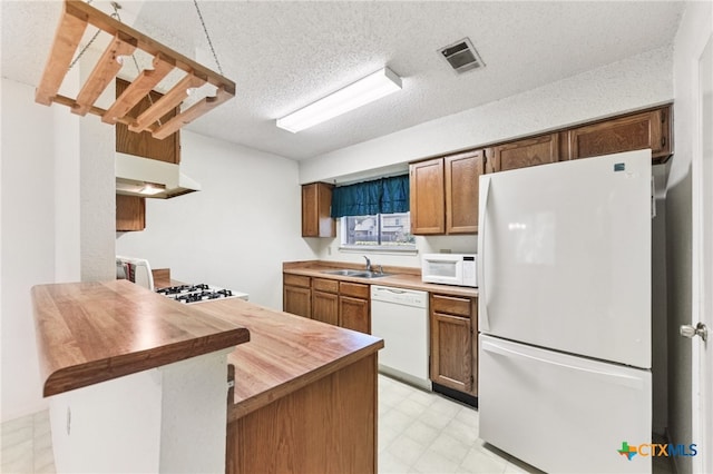 12219 Mosley Ln, Austin, TX 78727 - kitchen with white appliances, light flooring, wooden counters, a peninsula, and a textured ceiling