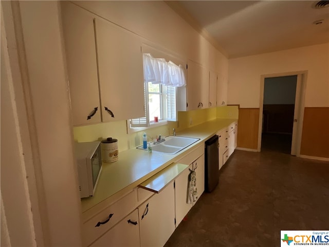 kitchen with white cabinetry, sink, and black dishwasher