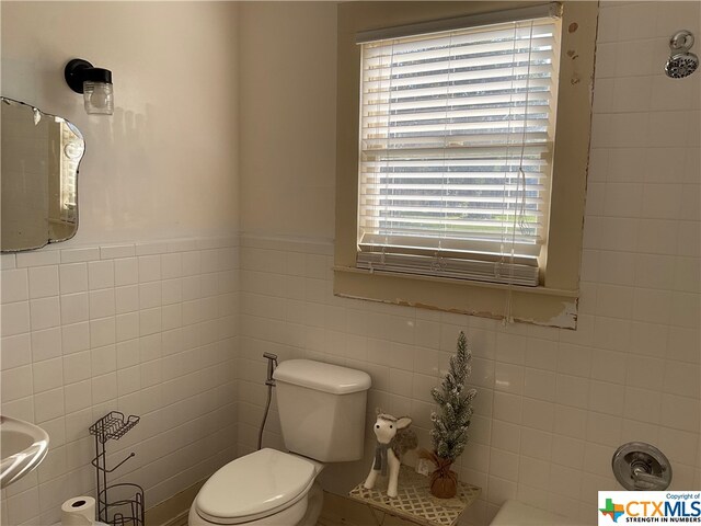 bathroom featuring toilet and tile walls