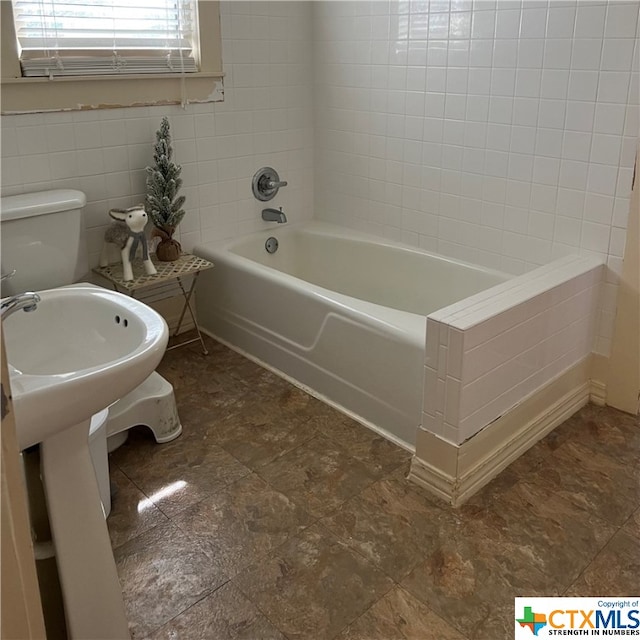 bathroom with toilet and tile walls