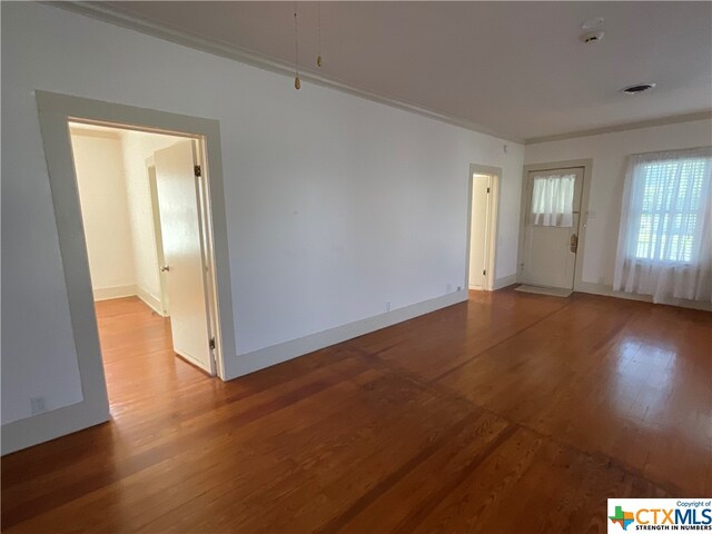 empty room with hardwood / wood-style floors and ornamental molding