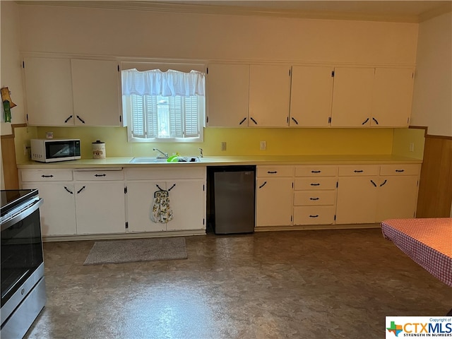 kitchen with black refrigerator, sink, stainless steel range oven, crown molding, and white cabinetry