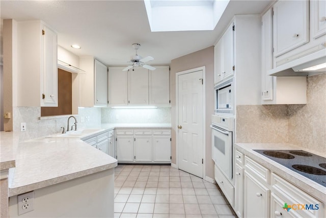 820 California Blvd, New Braunfels, TX 78130 - kitchen with white appliances, a sink, light countertops, a peninsula, and white cabinetry