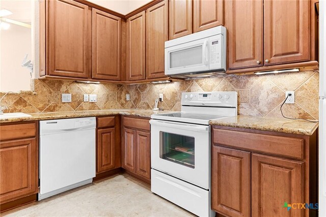 225 Anne Louise Dr, New Braunfels, TX 78130 - kitchen with white appliances, brown cabinetry, light stone counters, and backsplash