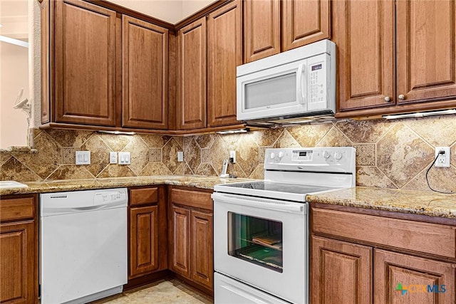 225 Anne Louise Dr, New Braunfels, TX 78130 - kitchen featuring white appliances, brown cabinetry, light stone countertops, and tasteful backsplash