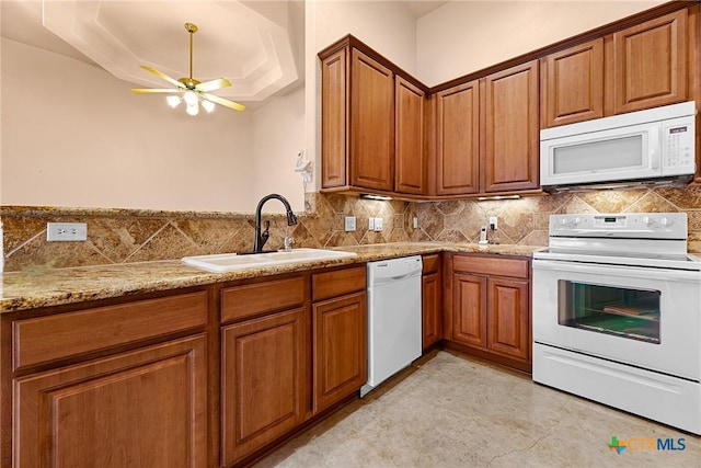 225 Anne Louise Dr, New Braunfels, TX 78130 - kitchen with white appliances, brown cabinetry, ceiling fan, light stone counters, and a tray ceiling