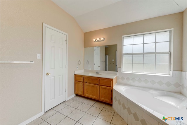 bathroom with vanity, tile patterned floors, a relaxing tiled tub, and vaulted ceiling