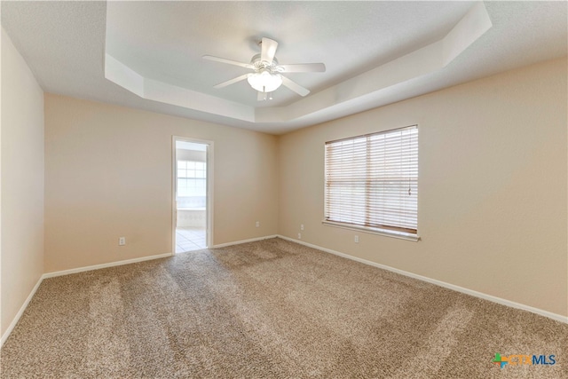 carpeted empty room featuring ceiling fan and a tray ceiling