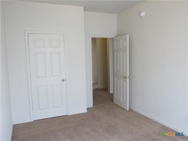 unfurnished bedroom featuring light carpet and a closet