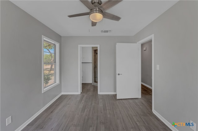 unfurnished bedroom featuring light hardwood / wood-style flooring, ceiling fan, a walk in closet, and a closet