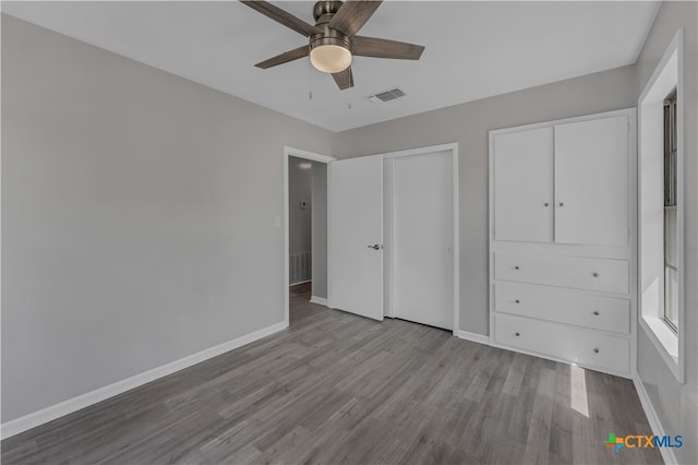 unfurnished bedroom with multiple closets, light hardwood / wood-style flooring, and ceiling fan