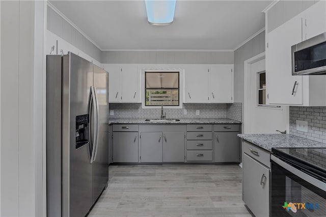 kitchen with light stone counters, crown molding, stainless steel appliances, sink, and light hardwood / wood-style floors