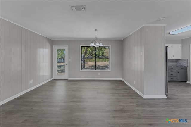 unfurnished dining area featuring hardwood / wood-style floors, an inviting chandelier, and crown molding