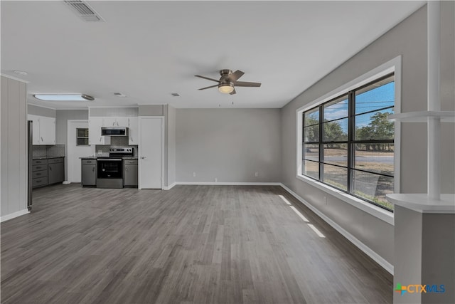 unfurnished living room with wood-type flooring, a healthy amount of sunlight, and ceiling fan