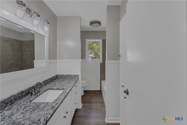 full bathroom featuring hardwood / wood-style flooring, vanity, toilet, and tiled shower / bath combo