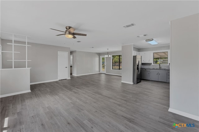 unfurnished living room with ceiling fan with notable chandelier, hardwood / wood-style flooring, and sink