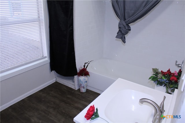 bathroom featuring wood-type flooring and a tub