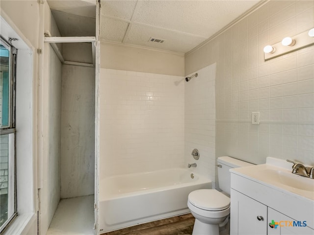 full bathroom with toilet, hardwood / wood-style flooring, vanity, tile walls, and tiled shower / bath