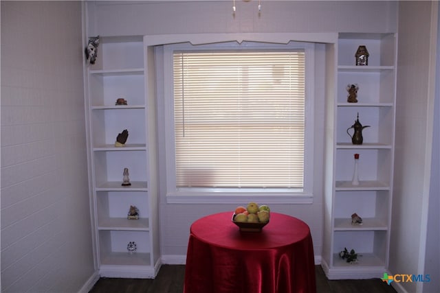 dining space featuring built in shelves, dark wood-type flooring, and a wealth of natural light