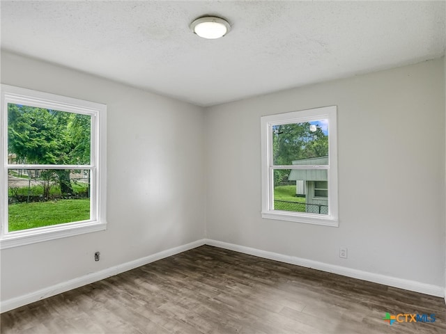 unfurnished room with a textured ceiling and dark hardwood / wood-style floors