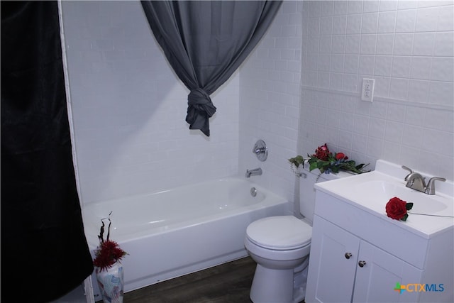 full bathroom featuring vanity, tiled shower / bath combo, wood-type flooring, tile walls, and toilet