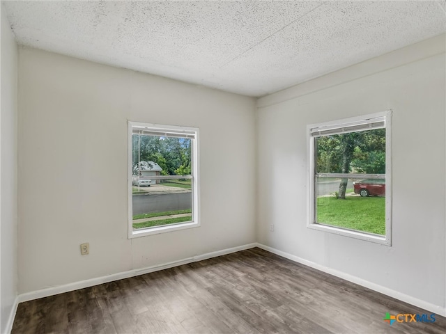 unfurnished room featuring dark wood-type flooring, a healthy amount of sunlight, and a textured ceiling