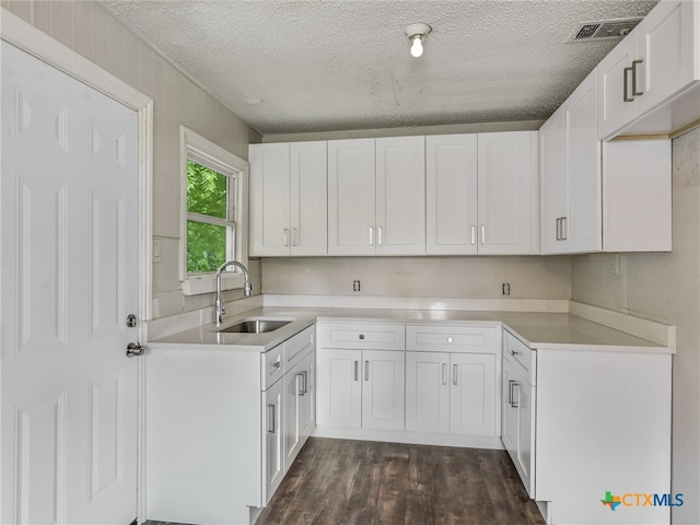 kitchen with dark hardwood / wood-style flooring, white cabinetry, sink, and a textured ceiling