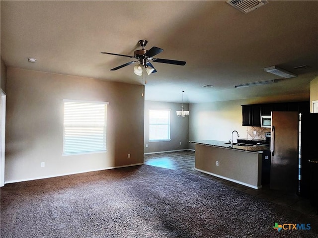 kitchen featuring sink, dark colored carpet, backsplash, decorative light fixtures, and black refrigerator