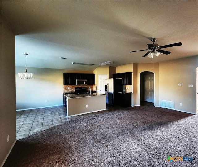 kitchen with dark carpet, a center island with sink, black range oven, ceiling fan with notable chandelier, and decorative backsplash