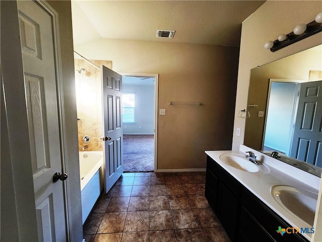 bathroom with a washtub, vanity, vaulted ceiling, and tile patterned flooring