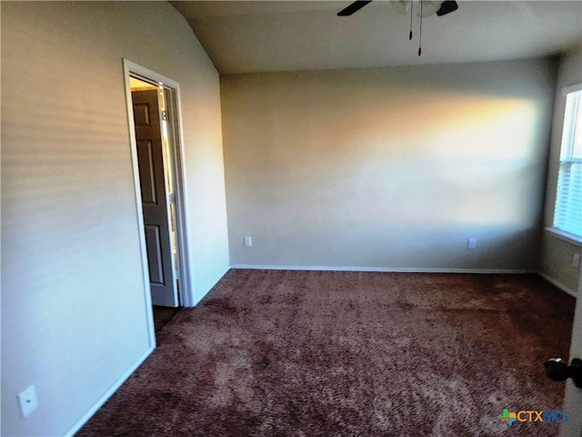 empty room with ceiling fan, lofted ceiling, and dark colored carpet