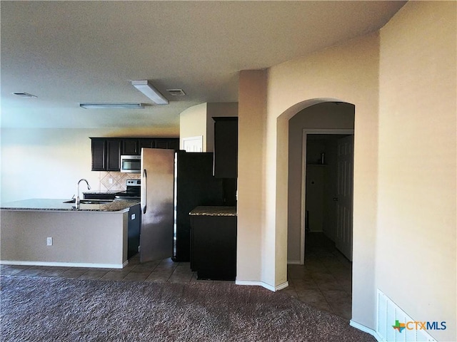 kitchen with dark tile patterned flooring, sink, a textured ceiling, appliances with stainless steel finishes, and tasteful backsplash