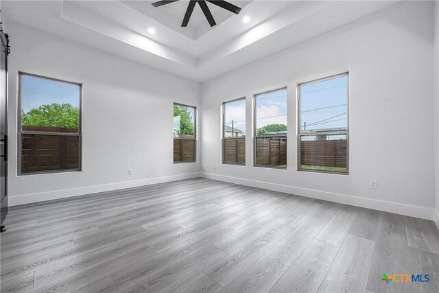 303 W Lane Ave, Manor, TX 78653 - empty room with a tray ceiling, a ceiling fan, healthy amount of natural light, wood finished floors, and recessed lighting