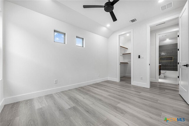 303 W Lane Ave, Manor, TX 78653 - unfurnished bedroom featuring a walk in closet, light wood-type flooring, vaulted ceiling, connected bathroom, and a closet